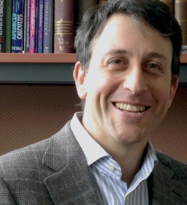 Prof. David Fisman smiling head shot in front of bookshelf