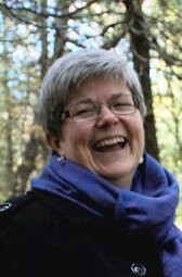 head shot, laughing, purple scarf, woods in background, short grey hair, glasses