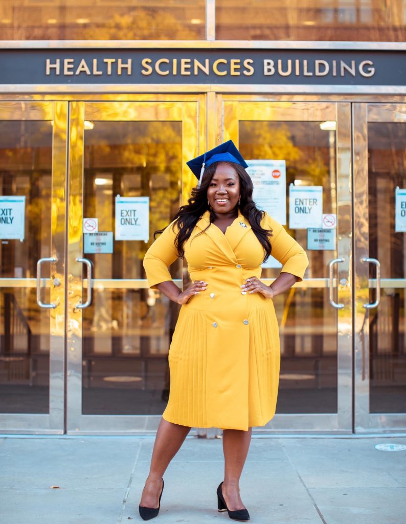 A photo of Maame De-Heer infront of the Dalla Lana School of Public Health building