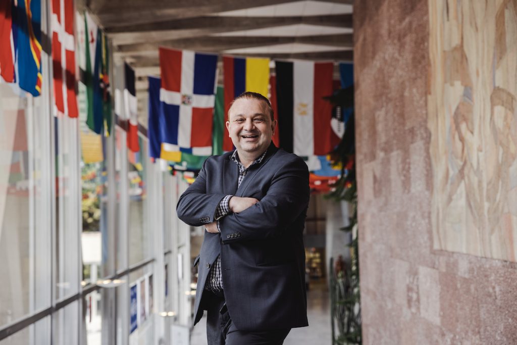 Garry Aslanyan in front of the WHO, wearing suit with arms folded