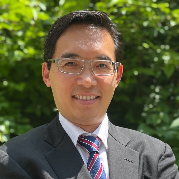 Nelson Lee in grey suit with tie, glasses