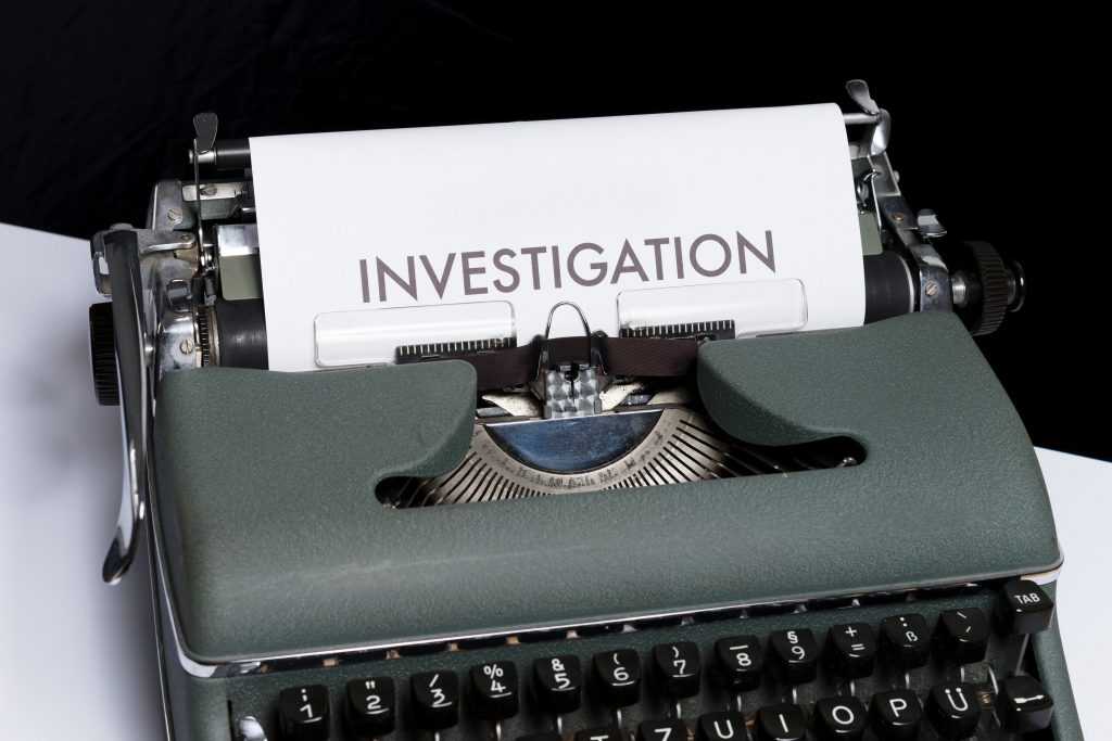 photo of old typewriter with investigation typed in large letters on white sheet of paper