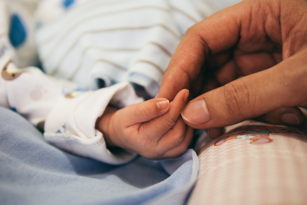 Image of a mother's hand holding a newborn's hand