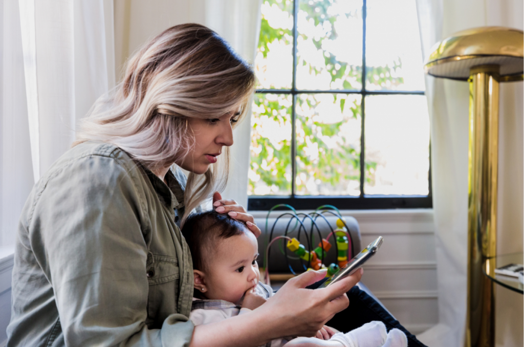 A worried mom holding a baby makes a call on her cellphone